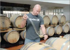  ??  ?? PROGRESS CHECK: Buitenverw­achting winemaker Brad Paton draws a sample of his 2011 Maximus.