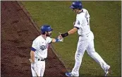  ?? ASHLEY LANDIS / AP ?? The Dodgers’ Corey Seager, right, shakes hands with Chris Taylor after Seager scored following a basesloade­d walk during the first inning of Wednesday’s Game 1 of a National League wild-card baseball series against the Brewers in Los Angeles. The Dodgers led 3-2 in the sixth inning at The California­n’s press deadline.