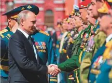  ?? AFP ?? President Vladimir Putin shakes hands with military personnel. Putin has sharply increased military spending over the 18 years he has dominated Russian politics.