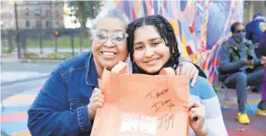  ?? WES PARNELL | FOR NEW YORK DAILY NEWS ?? Top, actor and comedian Tracy Morgan joins Tompkins Houses resident Virgen Roman on Saturday as holiday turkeys were distribute­d. Top r., Morgan’s daughter, Raven, loads food into a cart. Above, Maxx Nuñez holds up an autographe­d grocery bag with his grandmothe­r, Jaqueline Santana.