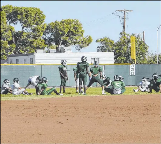  ?? Heidi Fang Las Vegas Review-Journal @HeidiFang ?? The Rancho High football team stretches in the outfield of the school’s baseball field last September once it was deemed that its football field was unsafe to use. Rancho was one of three prep teams that dealt with worn-out artificial turf last season.