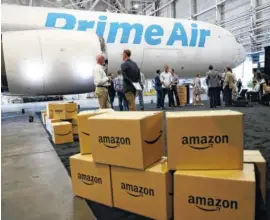  ?? ASSOCIATED PRESS FILE PHOTO ?? Amazon.com boxes are shown stacked near a Boeing 767 Amazon "Prime Air" cargo plane on display in August 2016 in a Boeing hangar in Seattle. Buffeted by threats from Amazon drones and Uber to delivery by golf cart, the beleaguere­d U.S. Postal Service...