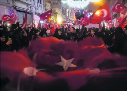 ?? Chris McGrath / Getty Images ?? Protesters hold Turkish flags as they sing songs and chant slogans outside the Dutch Consulate in Istanbul.