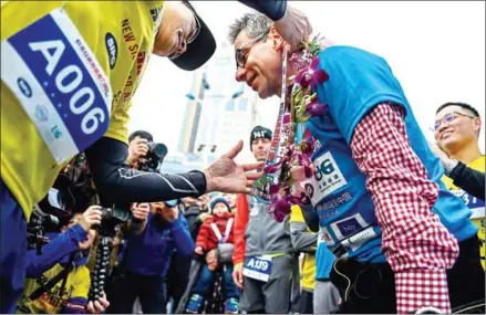  ?? CHANDAN KHANNA/AFP ?? German management consultant Kai Markus receives a medal as he finishes his journey at the Shanghai Internatio­nal port running track in Shanghai on Saturday.