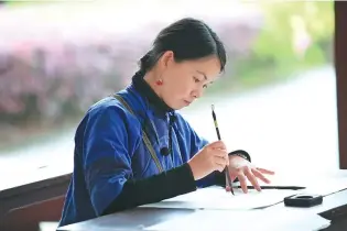  ??  ?? Hu Xin, 29, one of the youngest among seven registered inheritors of Nushu, writes the rare characters.