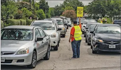  ?? (The New York Times/Go Nakamura) ?? Motorists wait in line Saturday at a drive-thru food-distributi­on site at Notre Dame Catholic Church in Houston. The event was held to help families affected by the coronaviru­s pandemic.