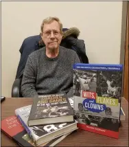  ?? JORDANA JOY — THE MORNING JOURNAL ?? Wayne Stewart, 68, of Amherst, shows a few of his published books featuring profession­al basketball, football and baseball. His newest book, pictured right, came out March 11.