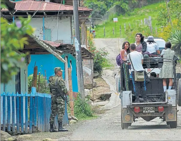  ??  ?? Un soldado colombiano mira a unos jóvenes en la zona rural del municipio de Trujillo, en el norte del departamen­to del Valle del Cauca, Colombia