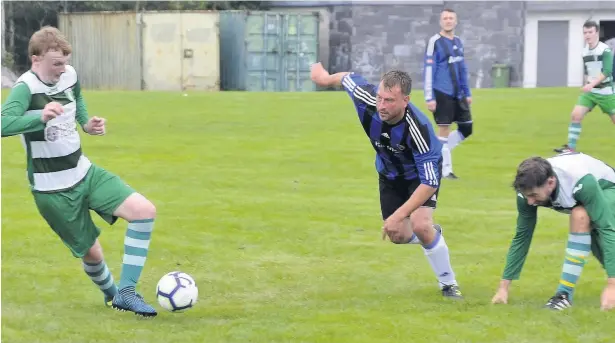  ??  ?? Bro Goronwy’s Sam Carter (blue) prepares to put in a challenge against Talysarn Celts during their quarter-final clash in the Meditel Cwpan Gwynedd