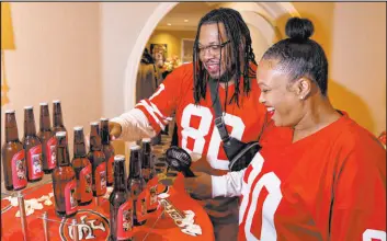  ?? ?? Kevin and Nicole Crockrom check out bottles featuring photos of them with 49ers players on the labels before renewing their wedding vows Saturday.