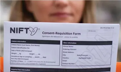  ??  ?? A woman holds a consent form accompanyi­ng the BGI Group’s prenatal test. Photograph: Jakub Stezycki/Reuters