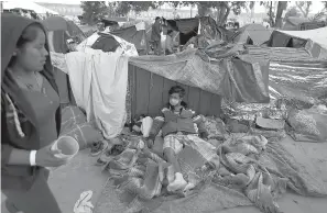  ?? AP Photo/Rebecca Blackwell ?? ■ A man wears a surgical mask, used by some migrants to protect against getting or spreading the infections rampant in their close living quarters, inside a sports complex sheltering more than 5,000 Central Americans Wednesday in Tijuana, Mexico. As Mexico wrestles with what to do with the thousands of people camped out in the border city of Tijuana, President-elect Andres Manuel Lopez Obrador's government signaled Tuesday that it would be willing to house the migrants on Mexican soil while they apply for asylum in the United States, a key demand of U.S. President Donald Trump.