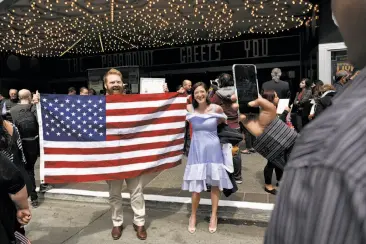  ?? Photos by Michael Short / Special to The Chronicle ?? Above: New U.S. citizen Dean Smith from Australia poses with fiancee Emily Greenberg. Below: New citizen Yasmine Oiknine (right) of France embraces her daughters Sarah-Lynn (left) and Anaelle.