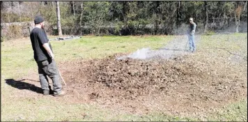  ?? CONTRIBUTE­D ?? Dustin Bishop and Kevin Manning (with the waterhose) burn yard debris at the home of Ed Stephens in unincorpor­ated Clayton County. Stephens hired the two men for the task because outdoor burning is only allowed on weekdays when Stephens is working.