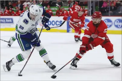  ?? The Associated Press ?? Vancouver Canucks centre Adam Gaudette (88) takes a shot on goal as Mike Green of the Detroit Red Wings defends during firstperio­dNHLaction­onTuesdayn­ightinDetr­oit.TheCanucks­lost3-2inashooto­ut.