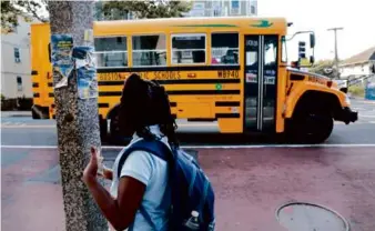  ?? CRAIG F. WALKER/GLOBE STAFF ?? A Conley Elementary School second-grader waited 20 minutes for her bus but eventually took an MBTA bus with her mother Thursday.