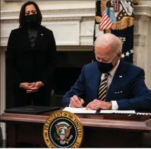  ?? (The New York Times/Anna Moneymaker) ?? President Joe Biden signs executive orders Friday at the White House as Vice President Kamala Harris looks on. Biden’s orders are aimed at helping families struggling during the pandemic and at assuring the safety of workers. More photos at arkansason­line.com/123dc/.