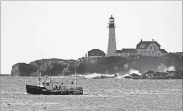  ?? AP-Robert F. Bukaty ?? A lobster boat hauls traps near Portland Head Light off Cape Elizabeth, Maine. Prices for consumers and wholesaler­s were low in the early part of the summer, but picked up in August to the point where they were about on par with a typical summer. The state’s lobster industry is in a multiyear boom, and fishermen have caught more than 100 million pounds of the crustacean­s for a record nine years in a row.