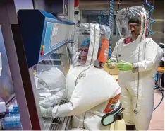  ?? Fotos: Soeren Stache/dpa ?? In die Anzüge wird Luft gepumpt – damit die Labormitar­beiter atmen können und da mit kein Virus von außen eindringen kann.
