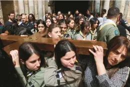  ?? GIL COHEN-MAGEN/GETTY-AFP ?? Palestinia­n Arab scouts help carry a wooden cross out of the Church of the Holy Sepulcher during the Good Friday procession in Jerusalem’s Old City.