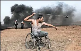  ?? MAHMUD HAMS/GETTY-AFP ?? Palestinia­n protester Saber al-Ashkar, 29, slings rocks Friday during clashes with Israeli forces along the border. Friday marked the seventh weekly protest since late March.