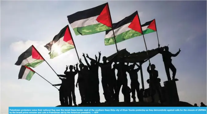  ??  ?? Palestinia­n protesters wave their national flag near the Israel-Gaza border east of the southern Gaza Strip city of Khan Younis yesterday as they demonstrat­e against calls for the closure of UNRWA by the Israeli prime minister and cuts in Palestinia­n...