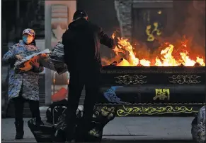  ?? (AP/Ng Han Guan) ?? Residents in Wuhan, China, burn paper offerings Friday for a relative who died from the coronaviru­s. Wuhan is the central Chinese city where the coronaviru­s was first detected nearly a year ago.