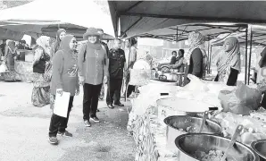  ??  ?? AMINAH melakukan pemantaun harga di bazar Ramadan Pekan Tomborungu­s, Kudat.