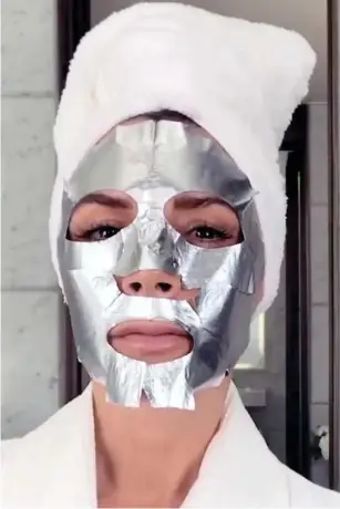  ??  ?? Cover-up: Mrs Beckham shows off her bizarre foil-like skin mask