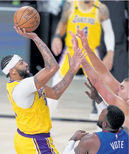  ?? Mark J. Terrill, The Associated Press ?? Los Angeles Lakers forward Anthony Davis, left, attempts a shot over Denver’s Paul Millsap, bottom, and Nikola Jokic during the second half Friday night in Lake Buena Vista, Fla.