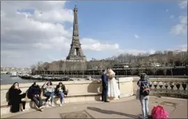  ?? Chesnot ?? NEWLYWEDS pose with the Eiffel Tower in the background last month in Paris. Vaccine verificati­on is a touchy subject in France, where inoculatio­ns lag.