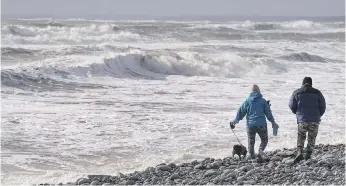  ?? DARREN CALABRESE, THE CANADIAN PRESS ?? Hikers walk along Lawrenceto­wn Beach Provincial Park in Lawrenceto­wn, N.S., as waves and heavy winds battered the coastline in January.