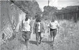  ??  ?? Flagstaff resident Richard Duran, left, Mayor Coral Evans and resident Dennis Baca walk through an alley Wednesday that they fear will become a major flood plain in upcoming monsoons in the Sunnyside community.