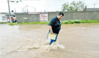  ??  ?? Hombre se arriesga a cruzar la calle, pese a la crecida de la corriente