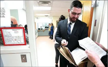  ?? NWA Democrat-Gazette/J.T. WAMPLER ?? Attorney Austin Lucas of Fayettevil­le talks Thursday to his client in a doorway outside of district court in Springdale. The current court facility has no rooms for attorneys to confer with clients, forcing them into the public hall.