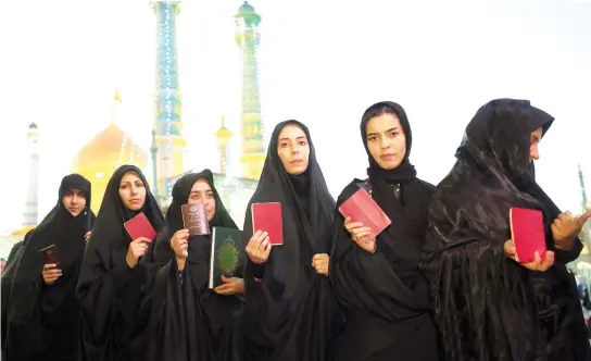  ??  ?? Iranian women hold their IDs as they wait in line to cast their votes for municipal and presidenti­al elections at a polling station at the Massoumeh shrine in the holy city of Qom, 130 km south of Tehran, Friday. (AFP)