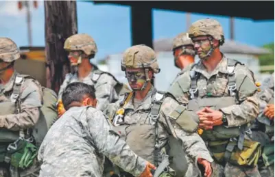  ??  ?? An Army instructor checks the equipment of a female Ranger student at Eglin Air Force Base, Fla., before a parachute jump. For the first time, two female students advanced to the final phase of Ranger School. Pfc. Yvette Zabala-Garriga, Army