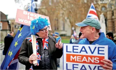  ??  ?? A Brexit supporter holds a placard next to anti-Brexit demonstrat­or during a protest opposite the House of Parliament / REUTERS
