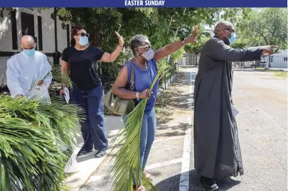  ?? CARL JUSTE cjuste@miamiheral­d.com ?? Chanel Jackson, Pastor Denrick Rolle, volunteers and church staffers wave as parishione­rs drive off after receiving their palms at Historic St. Agnes Episcopal Church’s drive-through Palm Sunday event March 28 in Overtown.