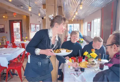  ?? EDDIE MOORE/JOURNAL ?? From left, Serena Konkin serves dinner to Serjoscha Wiemer, Toby Comradi and Tim Glaser at The Hollar restaurant in Madrid.