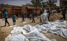  ?? AFP via Getty Images ?? People and health workers unearth bodies Tuesday found at Nasser Hospital in Khan Yunis in the southern Gaza Strip.