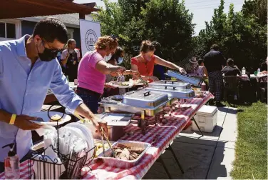  ?? Kristen Murakoshi / Special to The Chronicle ?? Friends of Lee Thomas serve themselves food at GrilleeQ’s grand opening Saturday in San Leandro.