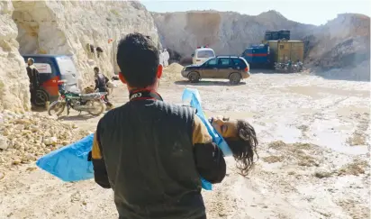  ?? (Reuters) ?? A SYRIAN MAN carries the body of a child killed by a suspected Syrian air force nerve gas attack on rebel-held Idlib yesterday.