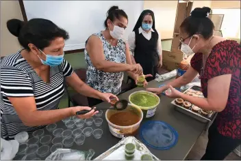  ?? Dan Watson/The Signal ?? (Above) Church members prepare salsa to go with the tamale dinners during the Our Lady of Perpetual Help tamale drive-thru dinner pick-up at OLPH in Newhall on Friday evening. The dinner is part of the church’s annual barbecue fundraiser. (Below) Father Emmanuel Delfin brings food to one of the dozens of cars that lined up Friday to pick up their tamale dinner orders.