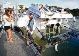  ?? Tanya White / Associated Press ?? A couple inspects a damaged boat after waves from a volcano eruption near Tonga swept into the marina Saturday at Tutukaka, New Zealand.