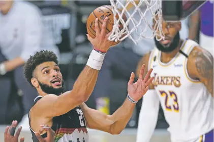  ?? MARK J. TERRILL/ASSOCIATED PRESS ?? Nuggets guard Jamal Murray shoots as the Lakers’ LeBron James looks on Tuesday in the Western Conference Finals in Lake Buena Vista, Fla. Murray scored 28 points including two late 3-pointers to halt a Lakers’ comeback attempt.