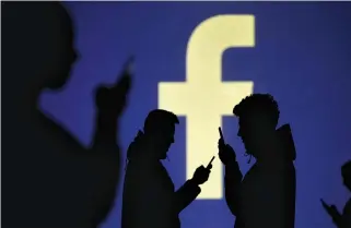  ?? REUTERS ?? SILHOUETTE­S of mobile users are seen next to a screen projection of Facebook’s logo in this March 28 picture illustrati­on.