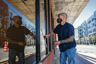  ?? Josie Norris / Staff photograph­er ?? Mike Ruiz washes the windows of the Milmo Lofts offices downtown. For the past two years, he’s worked at the building. He hustles to clean windows and offices and do odd jobs.