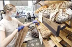  ??  ?? Maui Bread Company Store and Bake Shop
staffer Erika Kolist reaches for a loaf of German artisan bread Saturday morning. The specialtie­s of bread are named for the owners’ children, grandchild­ren and for friends, like a rye called Norbert Busch.