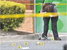  ?? KENNETH K. LAM/BALTIMORE SUN ?? A Baltimore police forensics officer photograph­s evidence where a robbery suspect was fatally shot in the parking lot of a drugstore at 6300 York Road on Wednesday.
